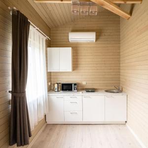 a kitchen with white cabinets and a microwave at Bona Natura Nameliai in Bražuolė