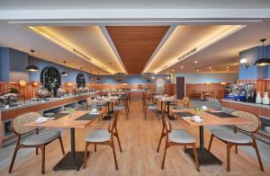 ASTON Inn Jemursari في سورابايا: مطعم بطاولات وكراسي خشبية وبار