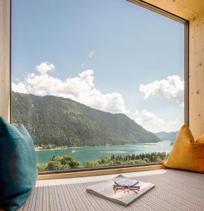 a room with a large window with a view of a lake at Hotel Nagglerhof am Weissensee in Weissensee