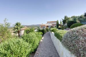 un jardín con arbustos y una casa al fondo en Villa élégante à Fréjus, Piscine, en Fréjus