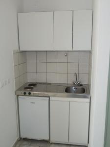 una pequeña cocina con fregadero y armarios blancos en Four Seasons Rooms & Apartments, en Ios Chora
