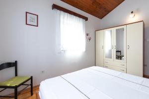 ein weißes Schlafzimmer mit einem Bett und einem Stuhl in der Unterkunft Marica A2 - Nr 1 in Baška
