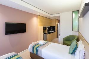 a hotel room with a bed and a flat screen tv at Kozi Suites Nairobi Airport in Nairobi