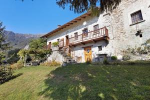 een groot stenen huis met een veranda en een balkon bij Al Pinone in Crevoladossola