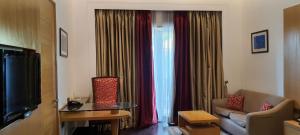 a living room with a couch and a window with curtains at The Umrao in New Delhi