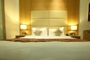 een groot bed in een hotelkamer met 2 lampen bij The Umrao in New Delhi