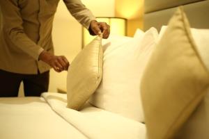 un hombre está poniendo almohadas en una cama en The Umrao, en Nueva Delhi