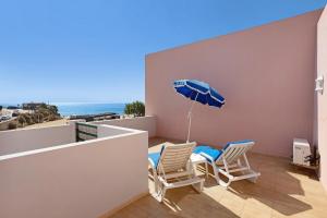 a balcony with chairs and an umbrella and the ocean at Cantinho da Sara in Portimão