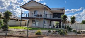 a house with palm trees in front of it at Agape Holiday Home with Pool table ,NBN Internet in Wallaroo