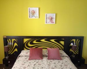 a yellow bedroom with a bed with two pink pillows at El Respiro verde in Denia