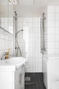 y baño blanco con lavabo y ducha. en Trendy Nordic Studio by Tram Stop, en Helsinki