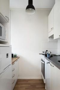 a kitchen with white cabinets and a stove top oven at Trendy Nordic Studio by Tram Stop in Helsinki