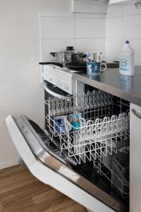 a dishwasher with dishes in it in a kitchen at Trendy Nordic Studio by Tram Stop in Helsinki