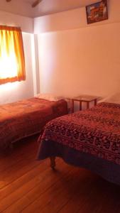 ein Hotelzimmer mit 2 Betten und einem Fenster in der Unterkunft Hostal Indigo Urubamba in Urubamba