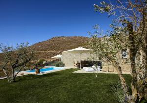 a house with a yard with a pool and an umbrella at Heliades Villas Suite with private pool in Andros