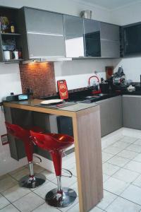 a kitchen with a bar with red stools in it at AnaLuiza Smarthome in Sao Jose do Rio Preto