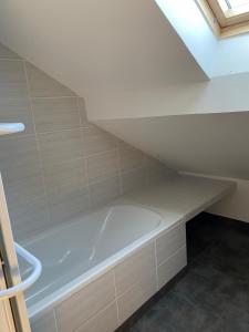 bañera blanca en el baño bajo el techo en Appartement 14 couchages vallée du Grésivaudan, en La Buissière