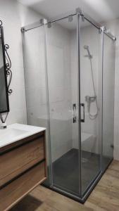 una ducha con una puerta de cristal junto a un lavabo en Casa Escola, en La Pobla de Segur