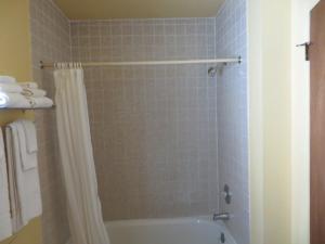 baño con cortina de ducha y bañera en Scottish Inn Winnemucca, en Winnemucca
