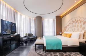 a hotel room with a bed and a flat screen tv at Cachet Boutique Kunming Artime in Kunming