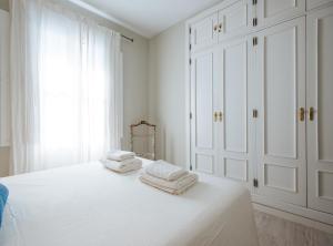 una camera da letto bianca con armadi bianchi e asciugamani su un letto di Latidos de Sevilla I - Deluxe con piscina a Siviglia