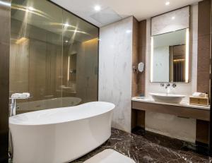 a bathroom with a tub and a sink at Cachet Boutique Kunming Artime in Kunming