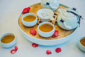a tray with three cups of tea and some roses at Cachet Boutique Kunming Artime in Kunming