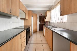 Una pequeña cocina con gabinetes de madera y un fregadero. en Casas Navio Guest House, en Johannesburgo