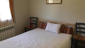 1 dormitorio con 1 cama blanca y 2 sillas azules en Apartamento Central, en Alp