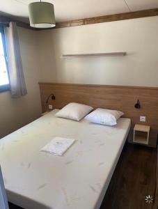 1 cama con 2 almohadas en una habitación en Bungalow Chalet 35 m2 camping l ile d or Saint-raphael, en Saint-Raphaël