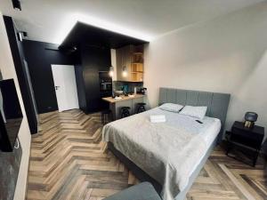 a bedroom with a large bed and a kitchen at Icon Apartaments Drobnera studio in Wrocław