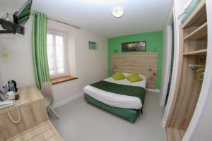 a bedroom with a bed with green walls and a window at Hotel Du Cheval Blanc in Saint-Pol-de-Léon