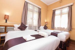 three beds in a room with windows at Impala Hotel Parklands in Nairobi