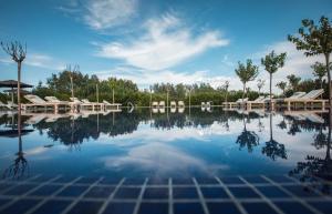una grande piscina d'acqua con alberi sullo sfondo di Les Cabanes de l'Oller del Mas a Manresa