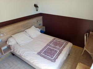 1 dormitorio con cama blanca y cabecero de madera en "Le Pigeonnier" chambre d'hôte, en Piégros-la-Clastre
