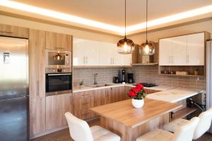 a kitchen with a wooden table and white chairs at Villa giannis in Vitalades
