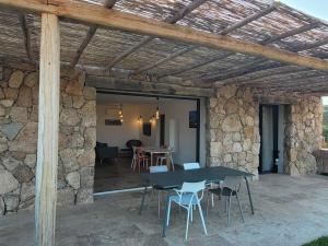 eine Terrasse mit einem Tisch, Stühlen und einer Steinmauer in der Unterkunft ARGIALE - ARGHJALE in Figari