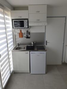 eine kleine Küche mit weißen Schränken und einem Waschbecken in der Unterkunft Superbe studio entièrement refait à neuf in La Grande-Motte