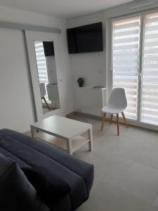 ein Wohnzimmer mit einem Sofa, einem Tisch und einem TV in der Unterkunft Superbe studio entièrement refait à neuf in La Grande-Motte