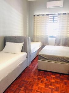 a room with two beds and a couch and a window at Alimama Guesthouse Melaka with Balcony in Malacca