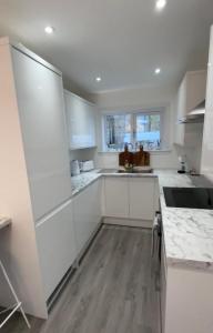 a white kitchen with white cabinets and a sink at Cosy Cottage in Stirling