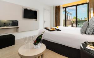 Grums Hotel & Spa في برشلونة: غرفة في الفندق مع سرير وزجاجة من الشمبانيا