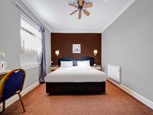OYO Bostons Manor Hotel في غرينفورد: غرفة نوم بسرير كبير ونافذة