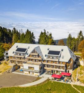 une vue aérienne sur un grand bâtiment avec des arbres en arrière-plan dans l'établissement Berghaus Freiburg - Appartement Hotel auf dem Schauinsland, à Oberried