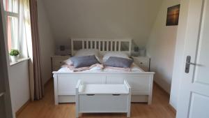 ein weißes Bett mit zwei Kissen auf einem Zimmer in der Unterkunft Haus Sonnenwind in Zingst