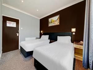 グリーンフォードにあるOYO Bostons Manor Hotelのベッド2台とデスクが備わるホテルルームです。