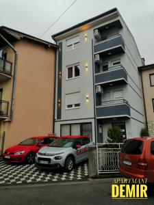 two cars parked in a parking lot in front of a building at Demir Apartmani in Novi Pazar