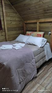 Cama grande en habitación con paredes de madera en cabanas luar, en São Francisco de Paula