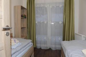 a bedroom with two beds and a window with green curtains at Apartamenty Lucky 188 in Belá