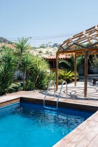 a pool with a wooden deck and a pergola at Casa da Mata SurfHouse in Costa da Caparica